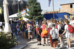 Scharen von Kindern warten bei sommerlichem Wetter auf Einlass in die Spielstadt Mini-München.
