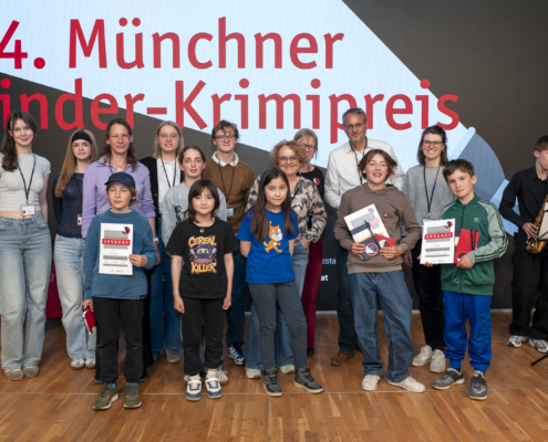 Das Foto zeigt die sechs Preisträger*innen und die Jury-Mitglieder bei der Verleihung des Kinder-Krimipreises 2026