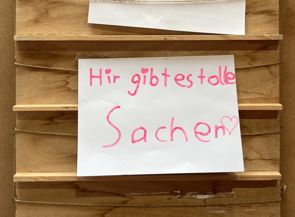 Das Foto zeigt einen handgeschriebenen Zettel mit der Aufschrift "Hir gibt es tolle Sachen".