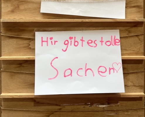 Das Foto zeigt einen handgeschriebenen Zettel mit der Aufschrift "Hir gibt es tolle Sachen".